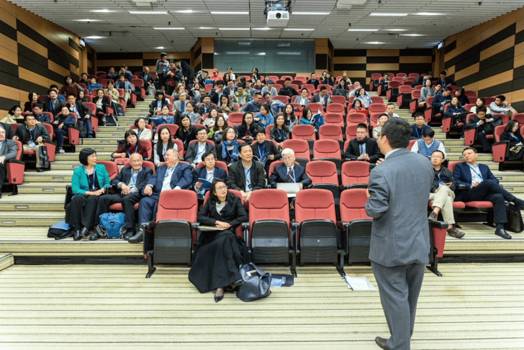 A person giving a speech in front of an audience in an auditorium.