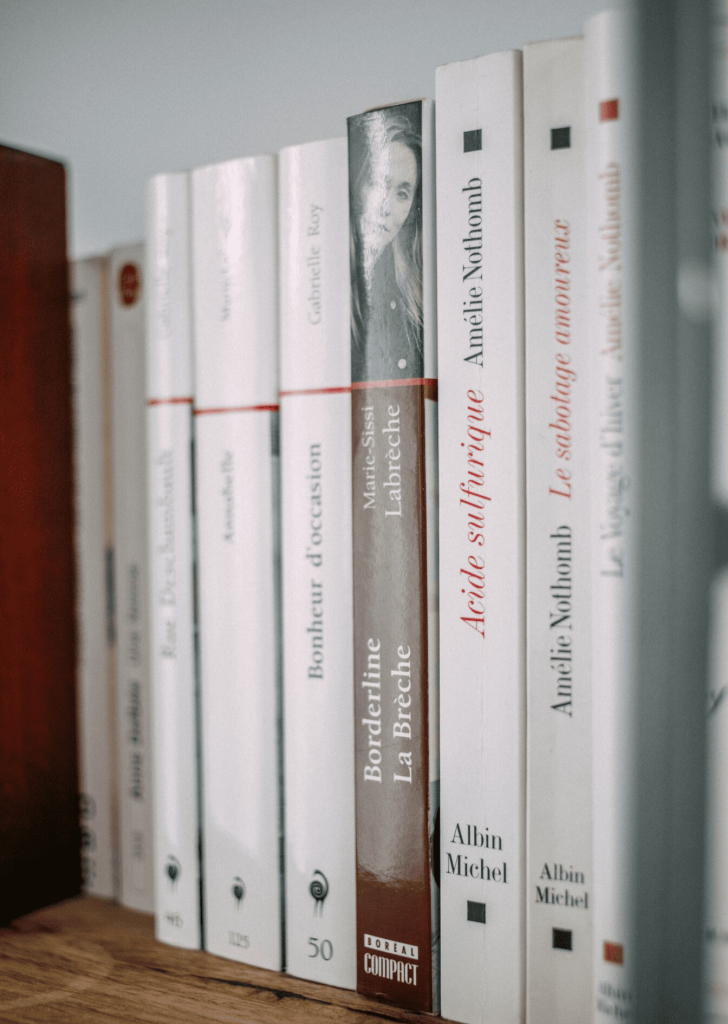 A pile of books on brown wooden surface.