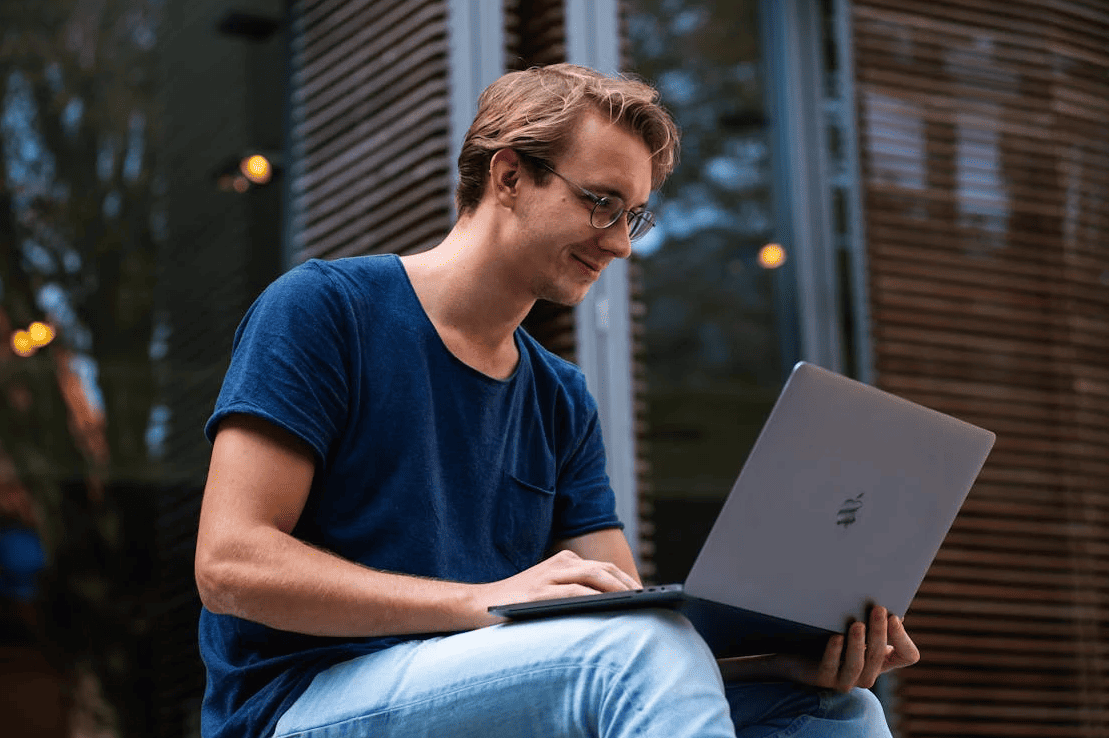 A man sitting with a laptop on his hands. 