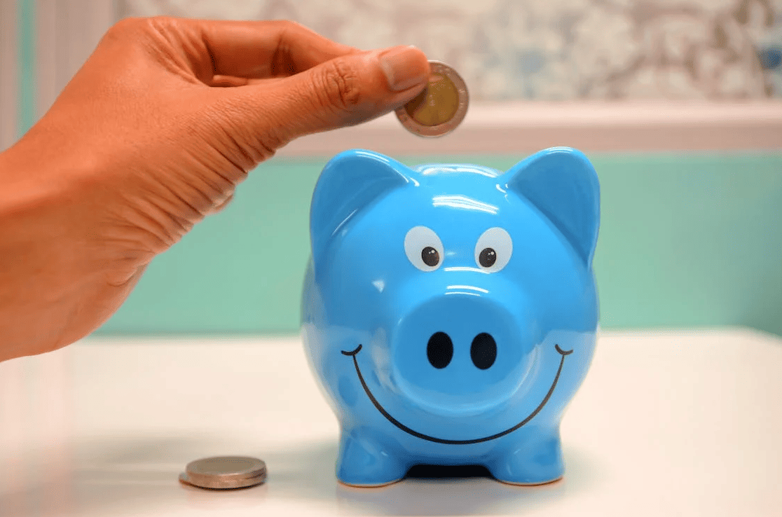 A person putting money into a blue piggy bank. 