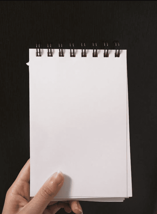 A person holding a notepad in their hand.