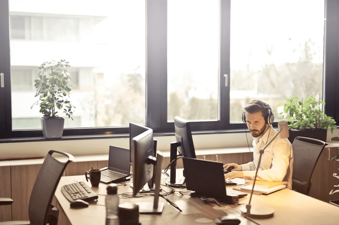 A man sitting in front of a computer with a headset. 