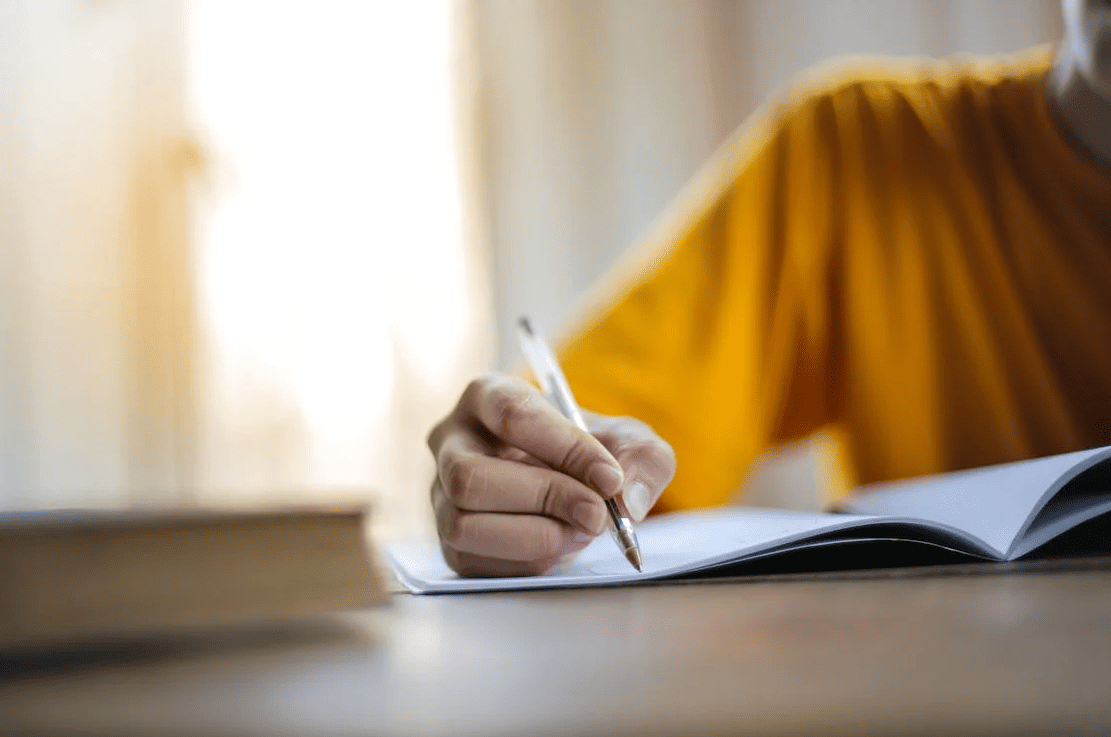 A person writing with pen in a notebook.