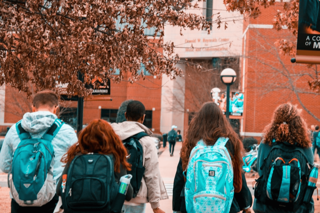 Students with backpacks walking toward a building.