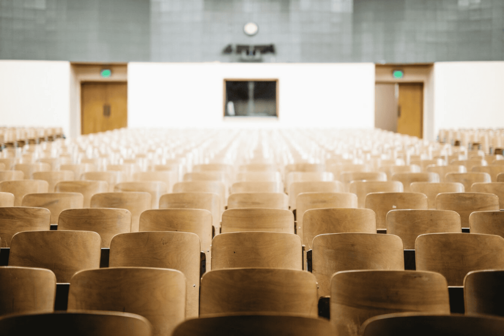 A college theater with many chairs and two entrance doors at the back.