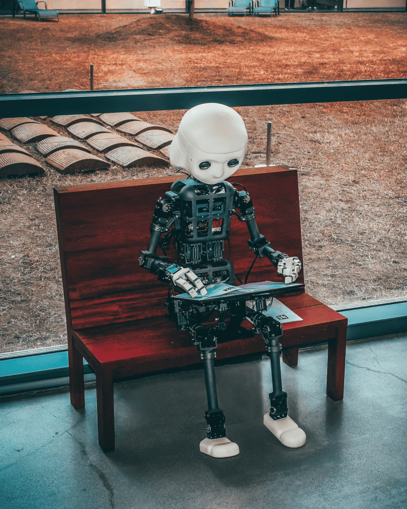 A black and white robot toy sitting on red wooden bench.