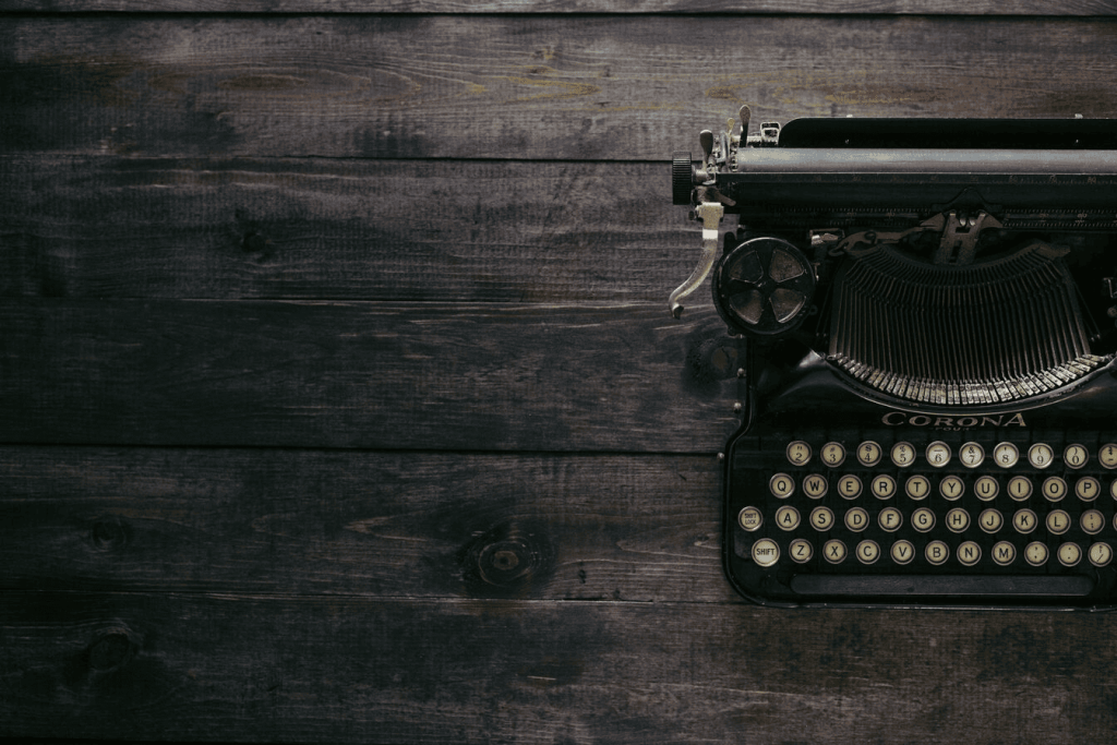 A black Corona typewriter on brown wood planks.