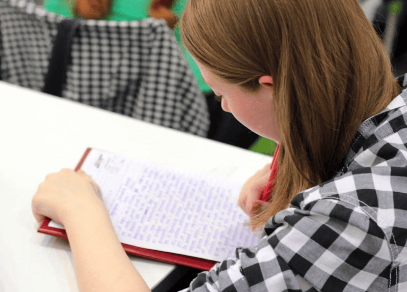 A student writing with pen and paper. 