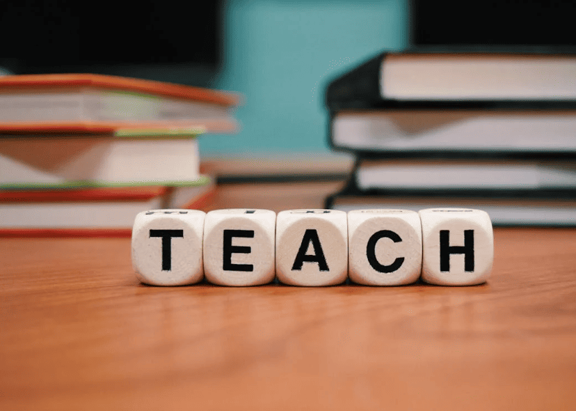 The word "teach" with cubes on a wooden table. 