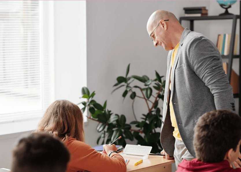 A teacher helping a student with their work in a classroom. 