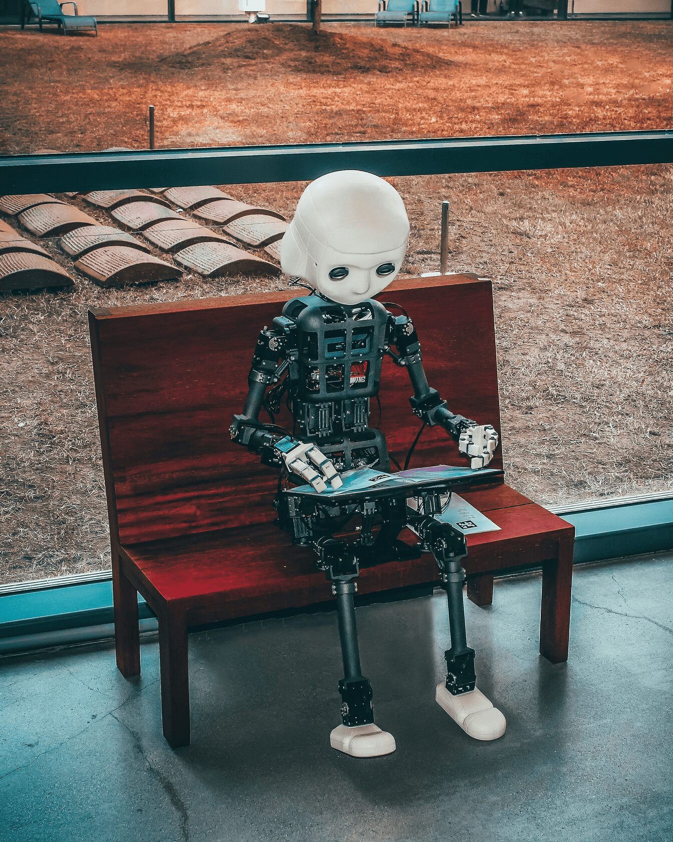 A black and white robot using a tablet on a bench.