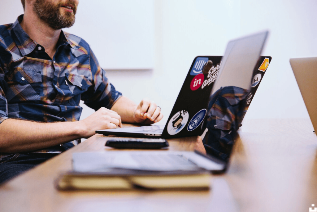 A person sitting at a desk with a laptop in front of them and another laptop next to them.