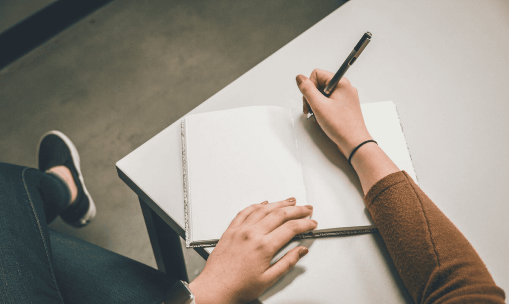 A person writing on white paper.