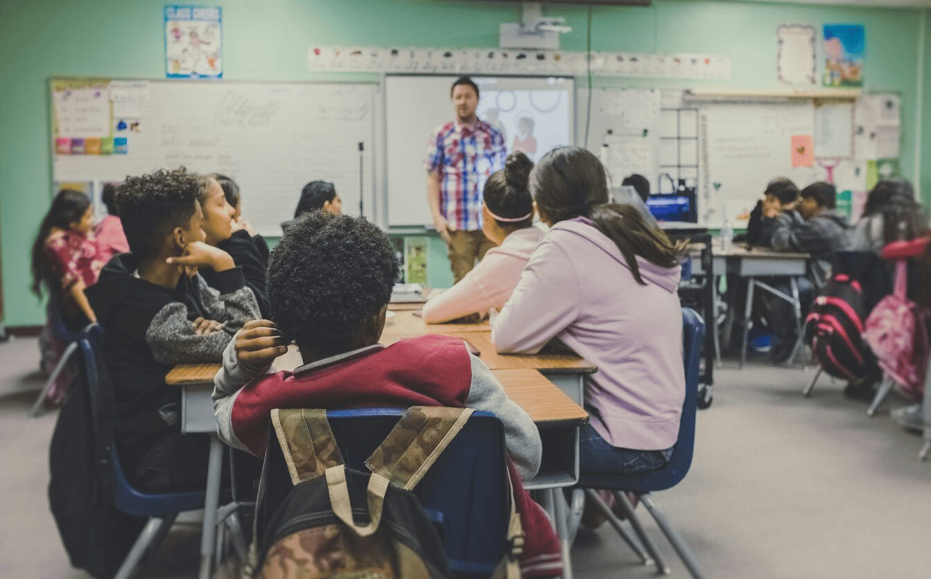 A teacher in front of a classroom of children. 