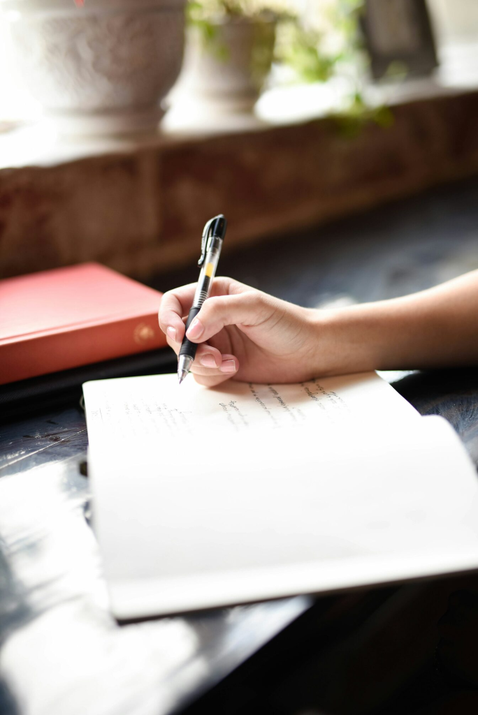 A person writing on a piece of paper with a pen.