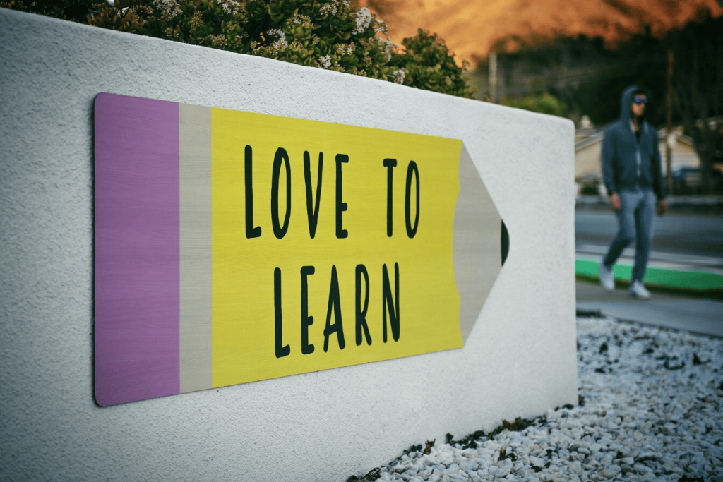 Uma sinalética a lápis &quot;love to learn&quot; numa parede branca.