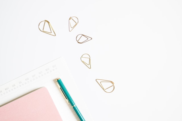 Writing paper, a pen, and paper clips on a white background. 