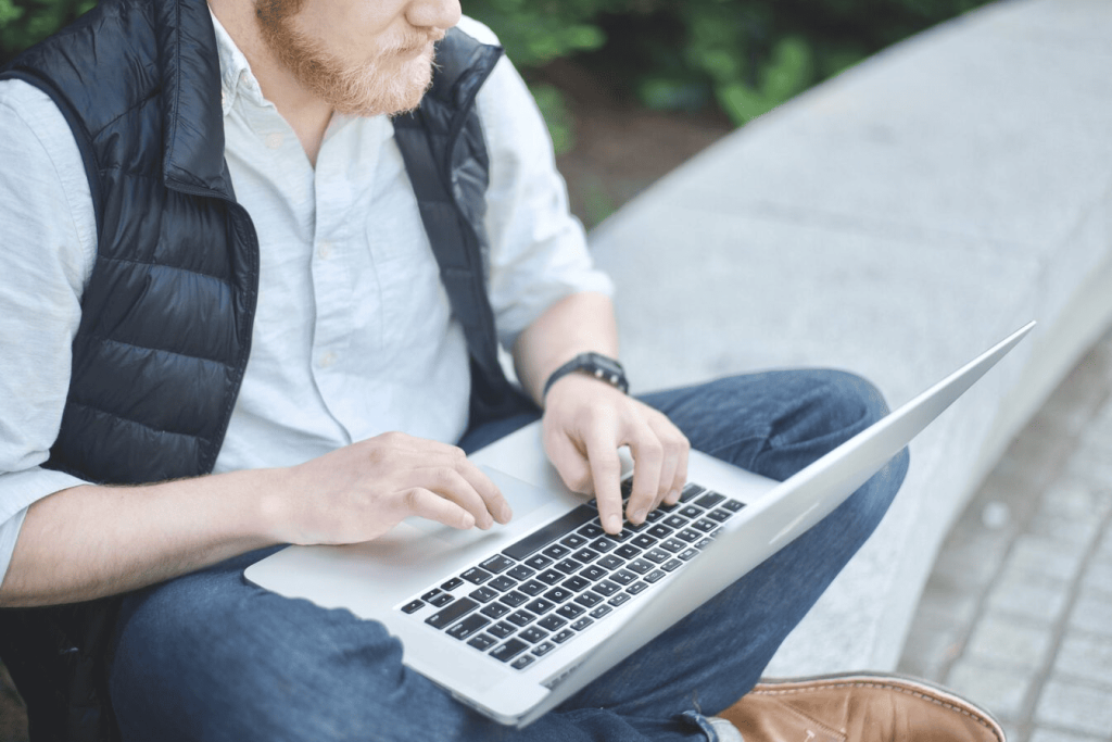 A man using a laptop outdoors. 