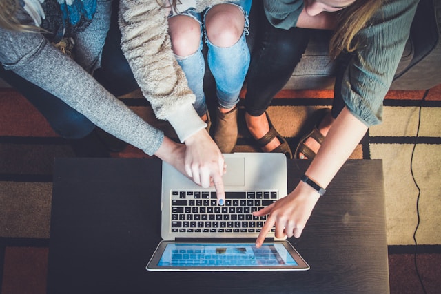 Three students pointing at a laptop screen. 