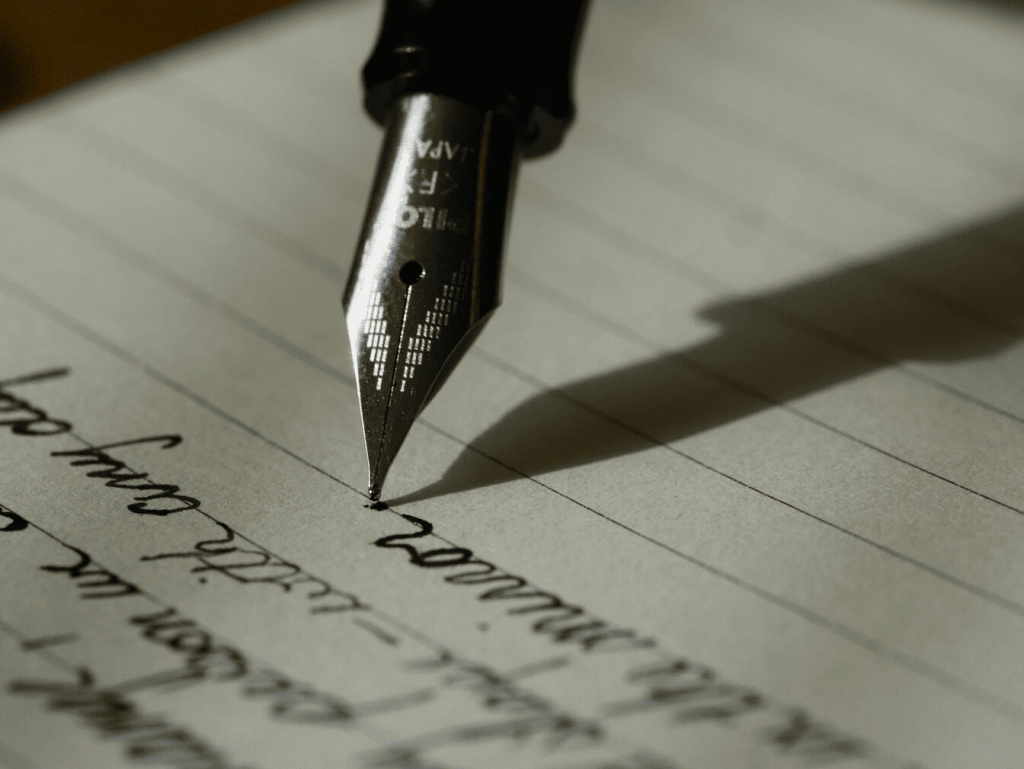 A black fountain pen writing on black lined paper.