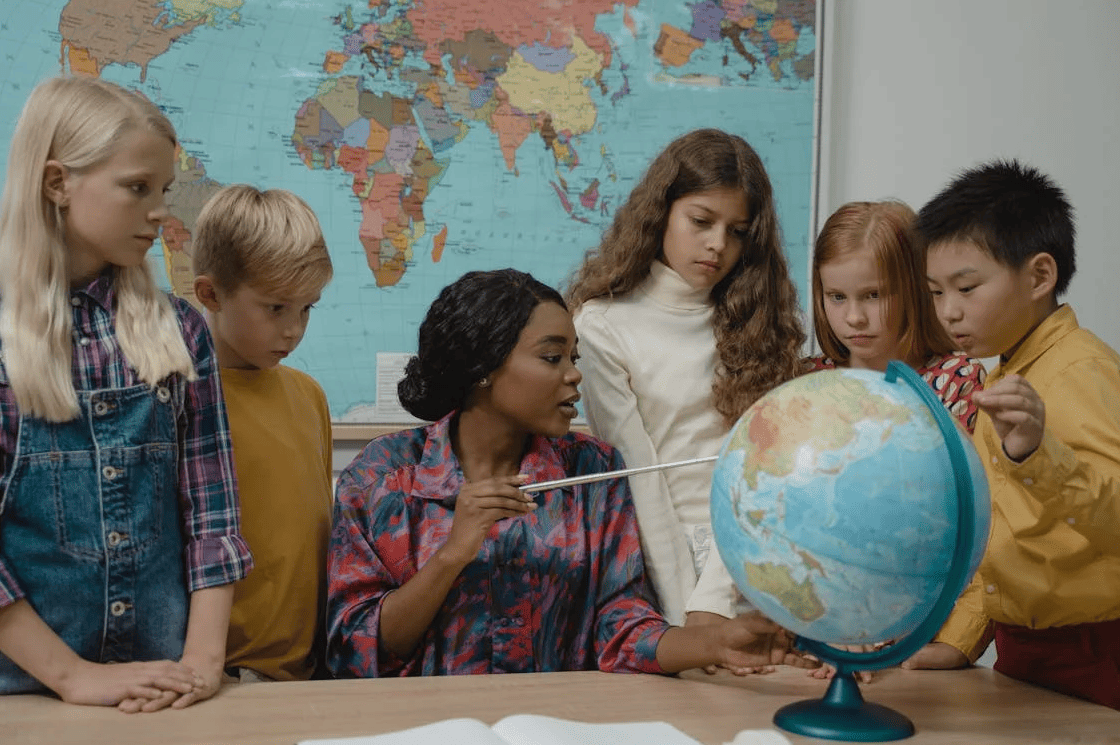 Een leraar met leerlingen in een klaslokaal voor een wereldbol. 