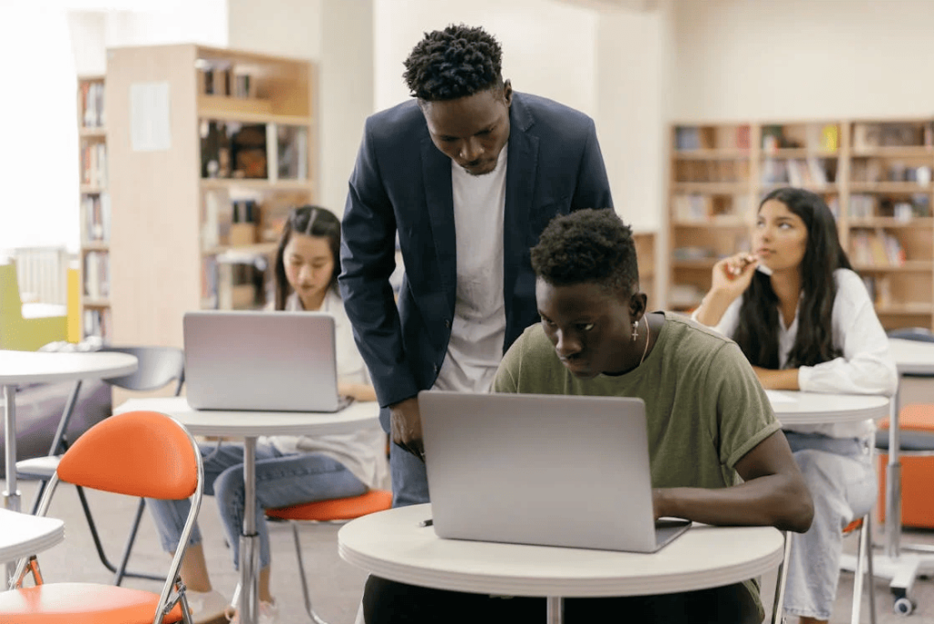 A teacher looking at the work of a student in a classroom. 