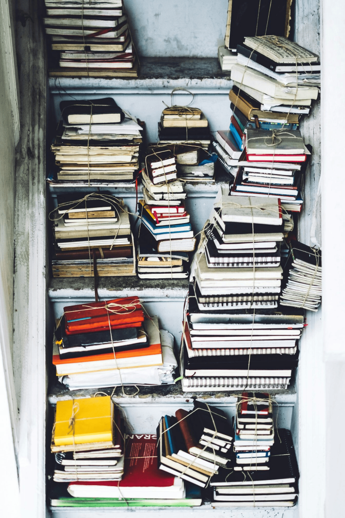 Lots of books piled up in a cupboard.