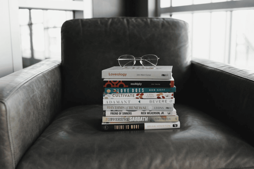 Books on top of one another on a black armchair.