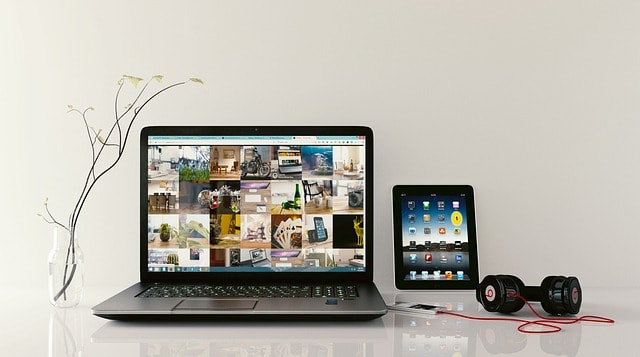 A laptop, a tablet, and a pair of headphones on a white surface.