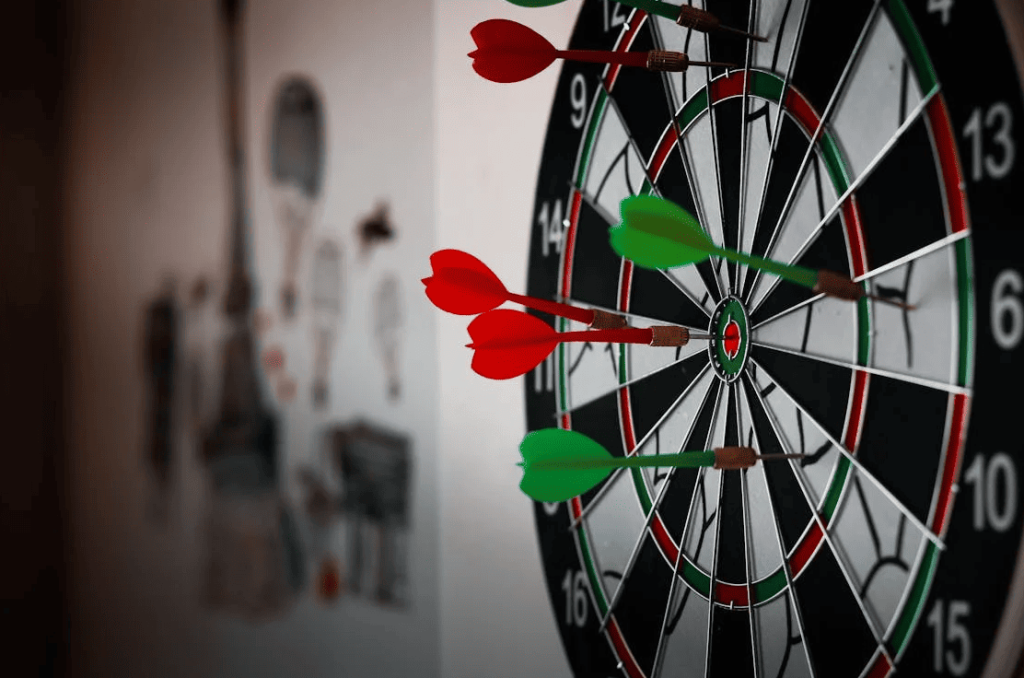 A dartboard with green and red darts. 