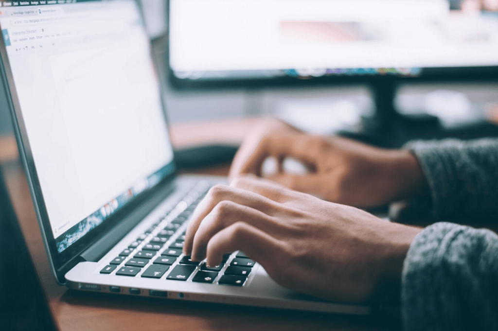 A person typing on a laptop with both hands. 