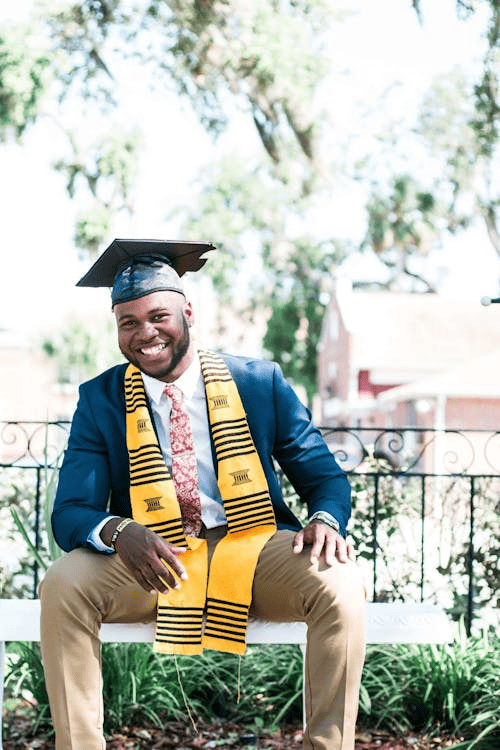 A man wearing a graduation cap and a yellow scarf.