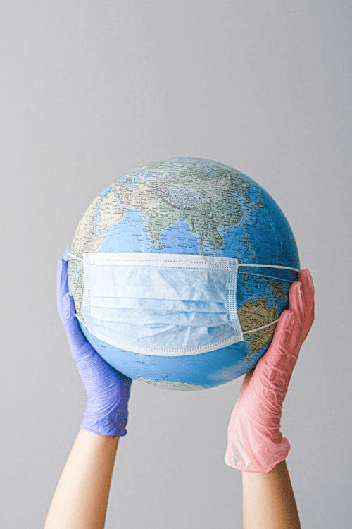 A person holding a globe with latex gloves. 