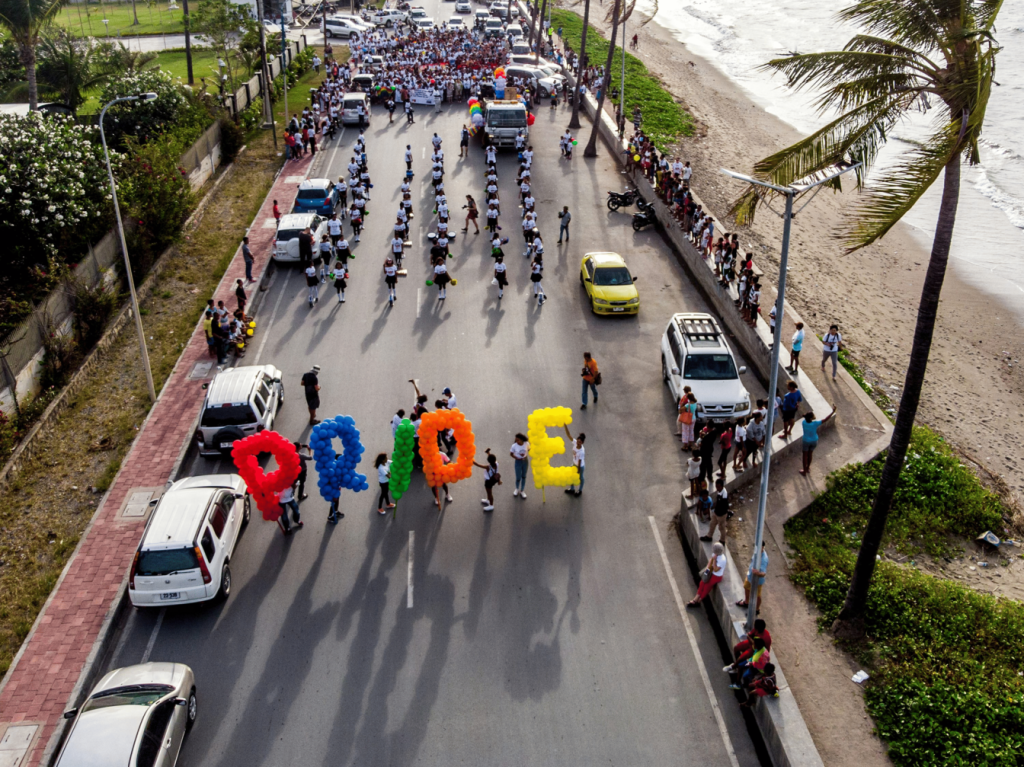 A group of people walking on the road carrying Pride balloons.