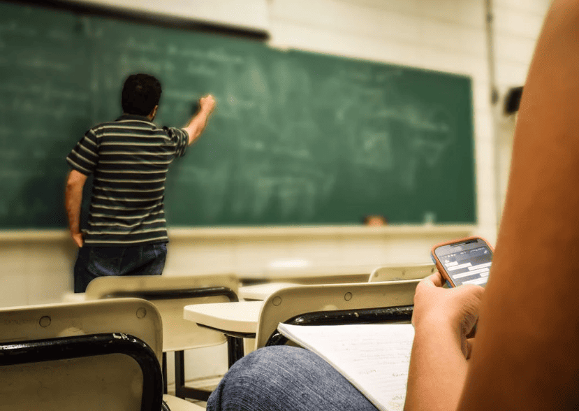 A teacher in a classroom writing on a board. 