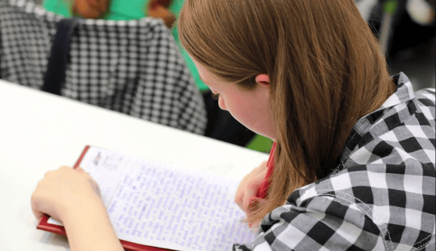 A female student writing on a piece of paper. 