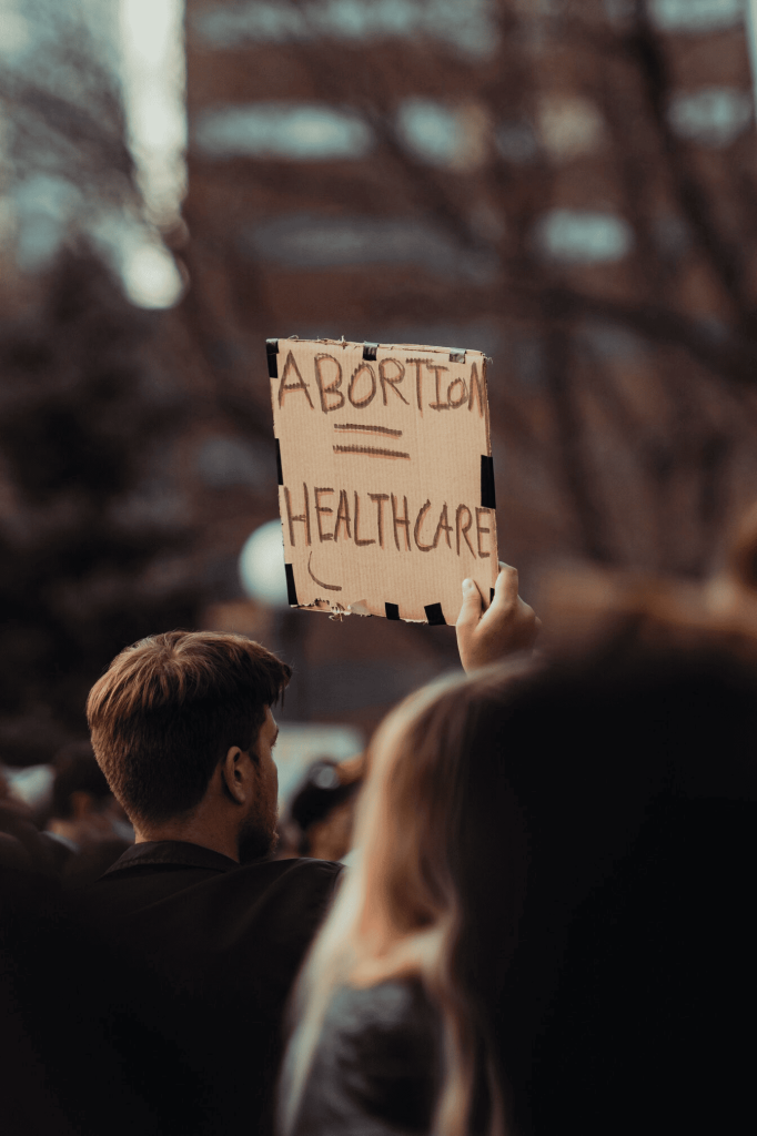 A man holding a sign that says "Abortion = Healthcare."