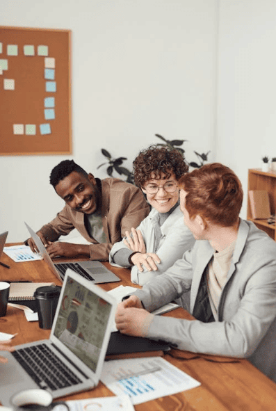 A team of office employees working around a wooden desk. 