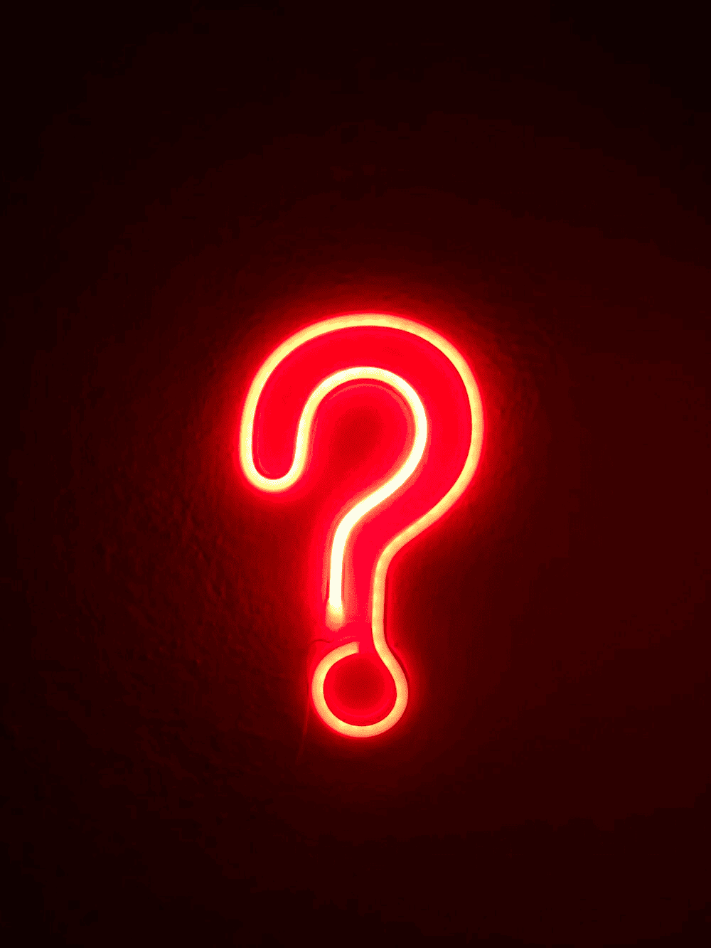 A red question mark with neon light on a dark background. 