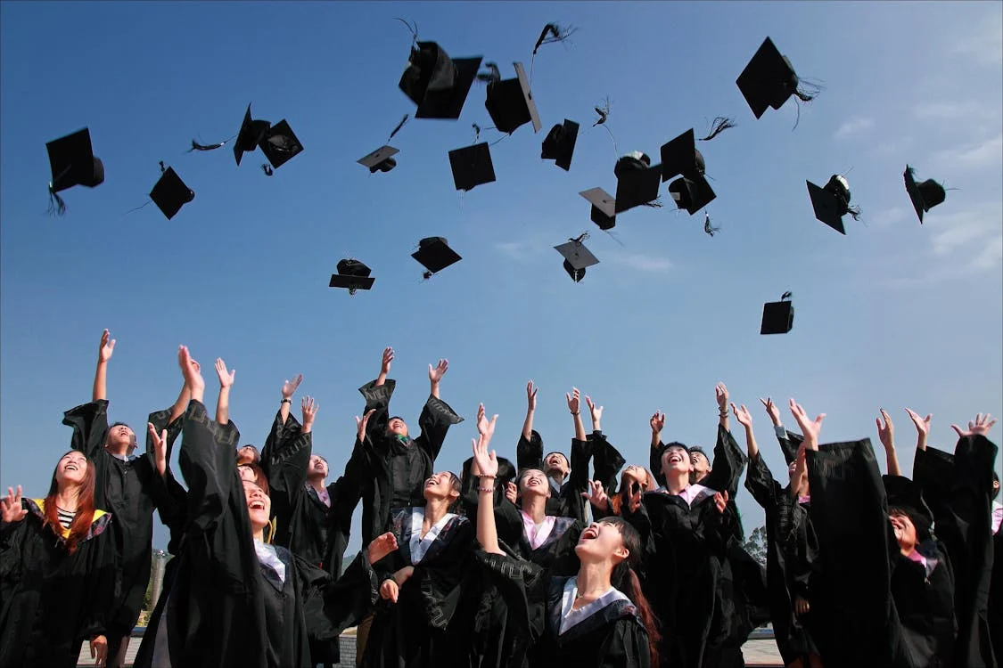 A group of students throwing their graduation hats in the air. 