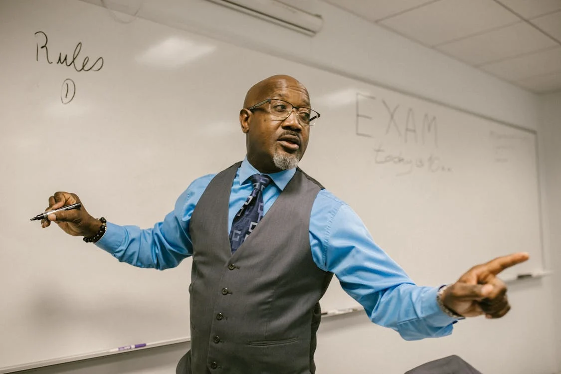 A professor standing in front of a whiteboard. 