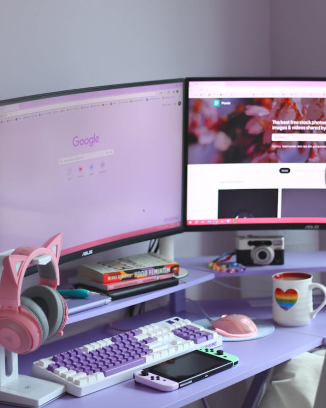 Colorful desk set up with a keyboard, headphones, a mouse, books, and 2 large monitors with Google pulled up in the browser.