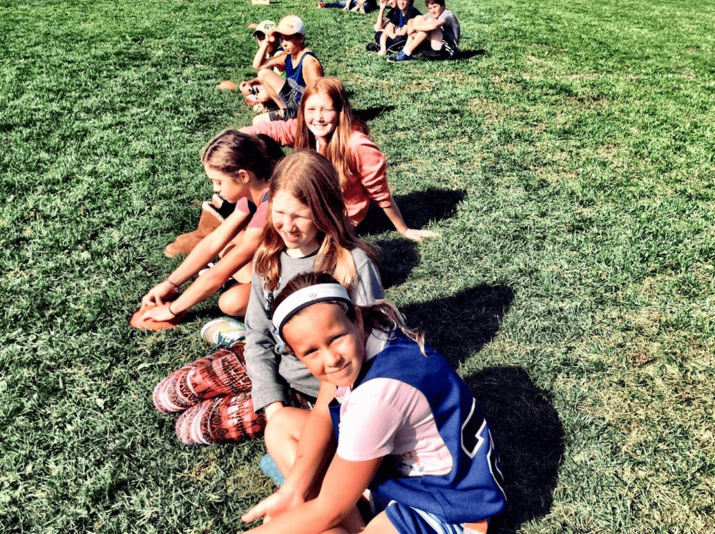 A group of children sitting in a field. 