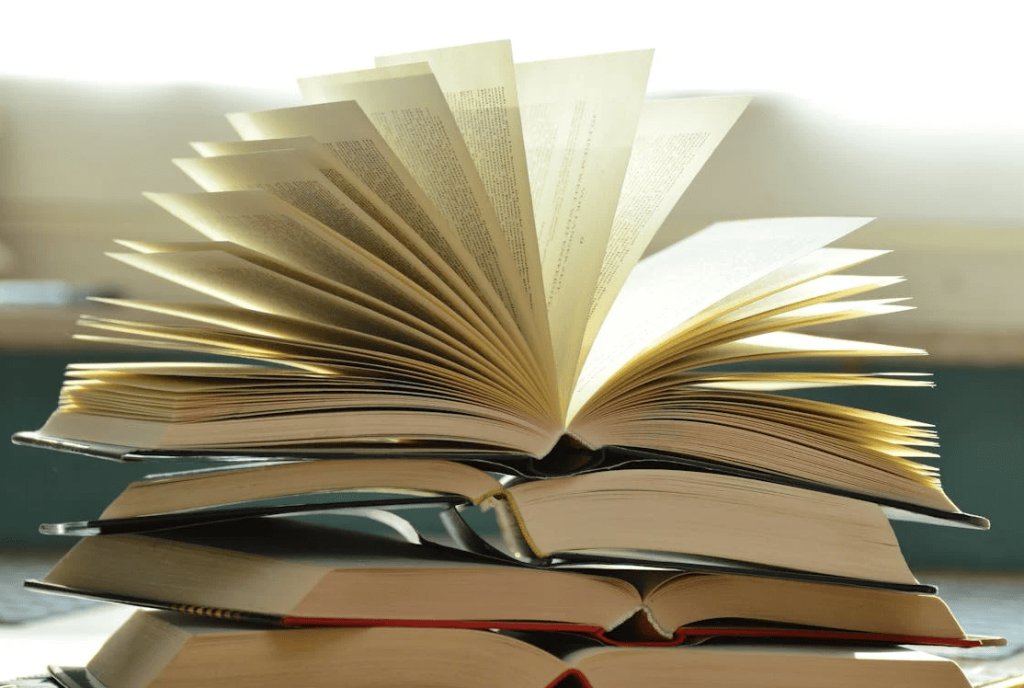 An open book sitting on a pile of books. 