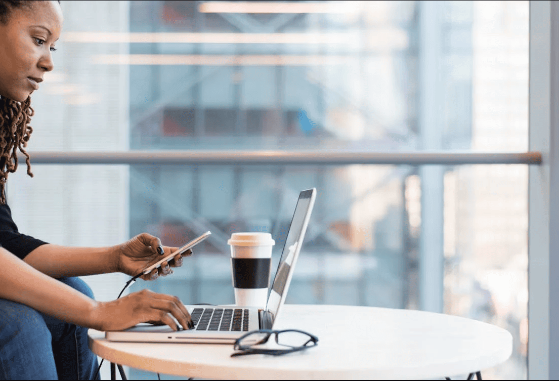 A woman using a laptop and smartphone. 