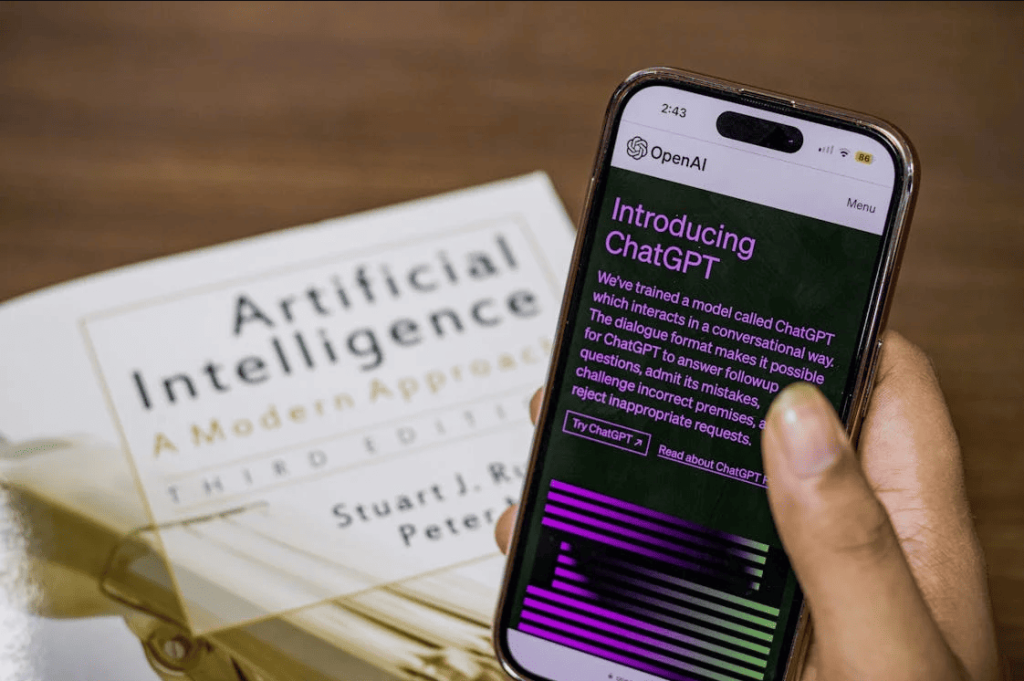 A person using an AI app with an "Artificial Intelligence" book in the background. 