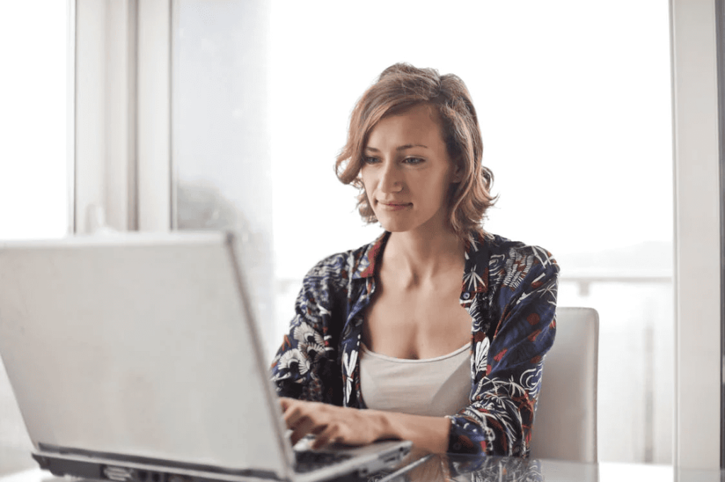 A woman using a laptop on a desk. 