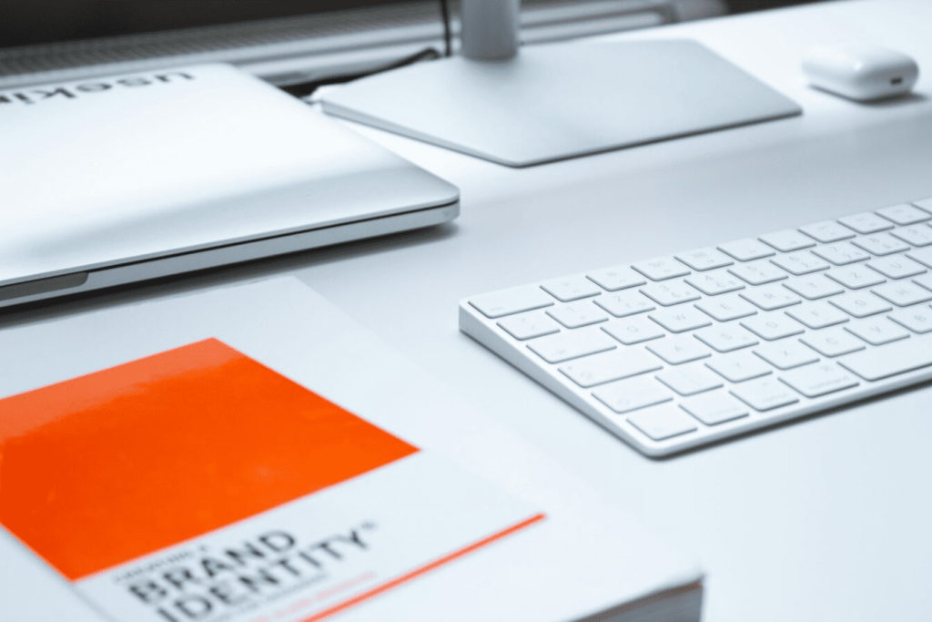 A book with the words "Brand identity" on its cover next to a keyboard and laptop. 