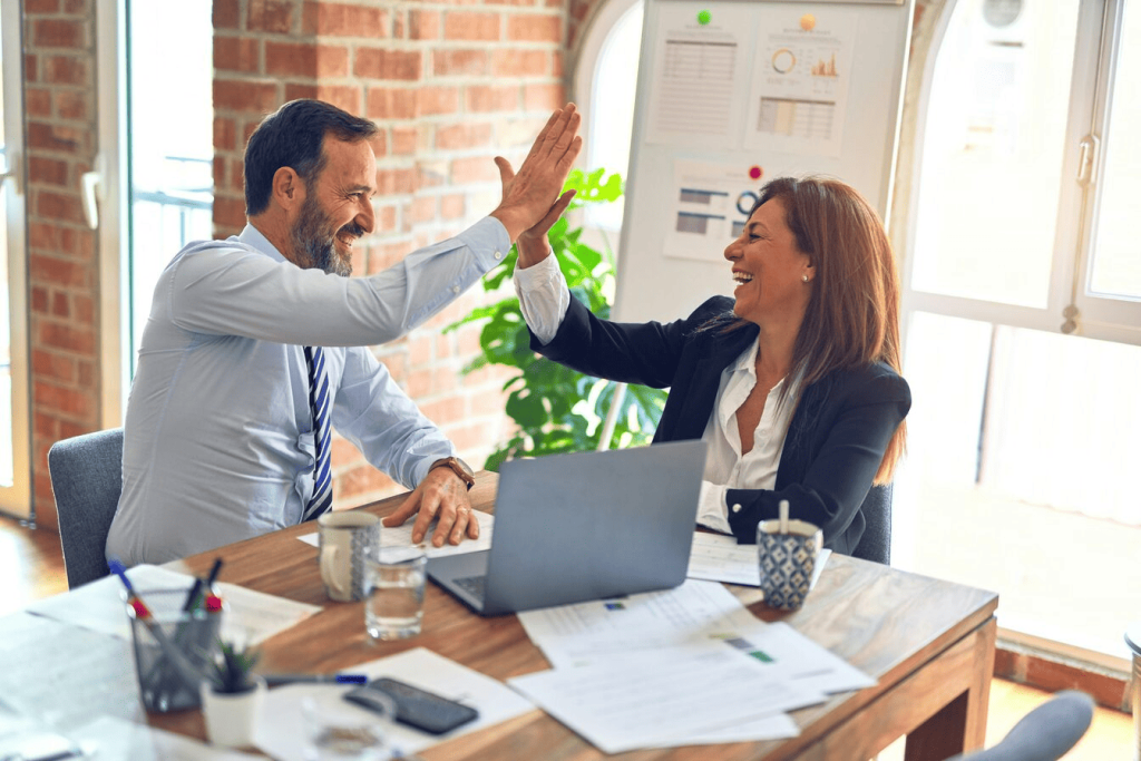 A man and woman doing a high five in an office. 