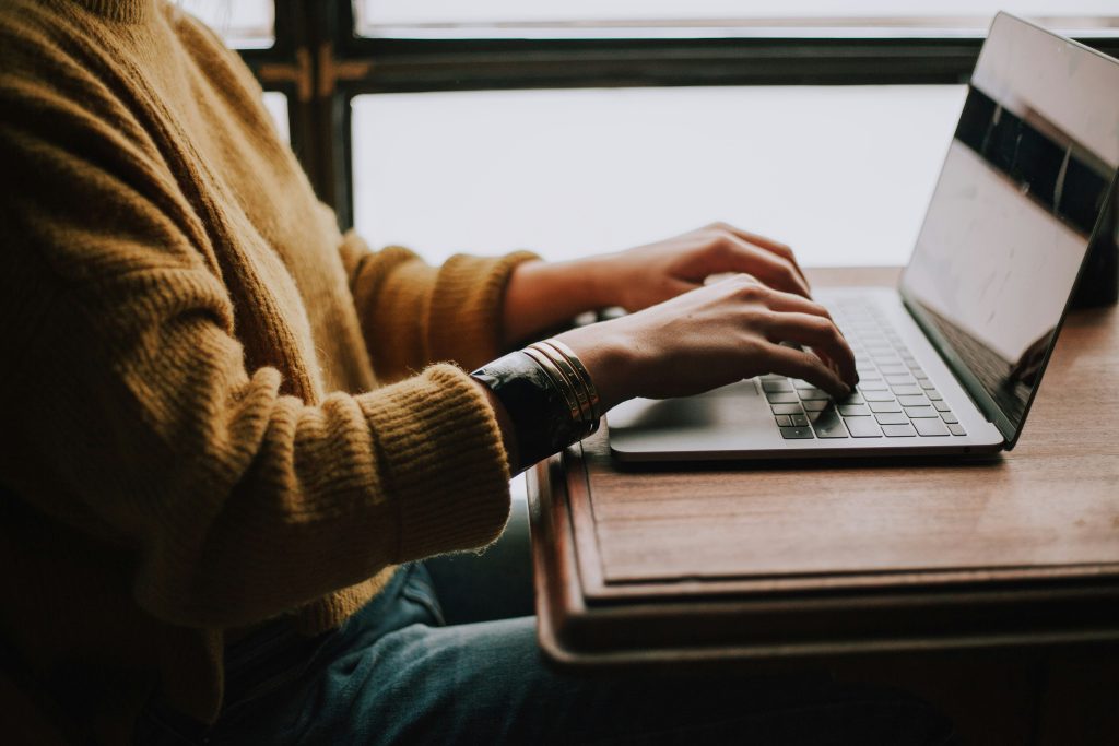 A person sitting in front of a laptop and typing.